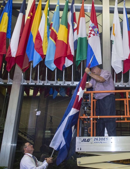 Workers at the US State Department add the Cuban flag at to the display inside the main entrance early on Monday morning.