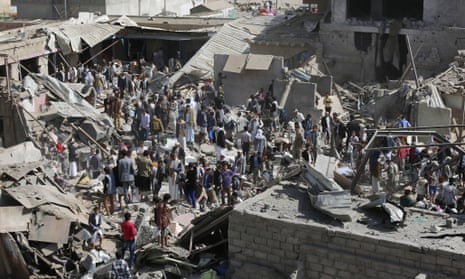 People gather on the rubble of shops destroyed by a Saudi-led airstrike at a market in Sanaa, Yemen,  July 20, 2015.