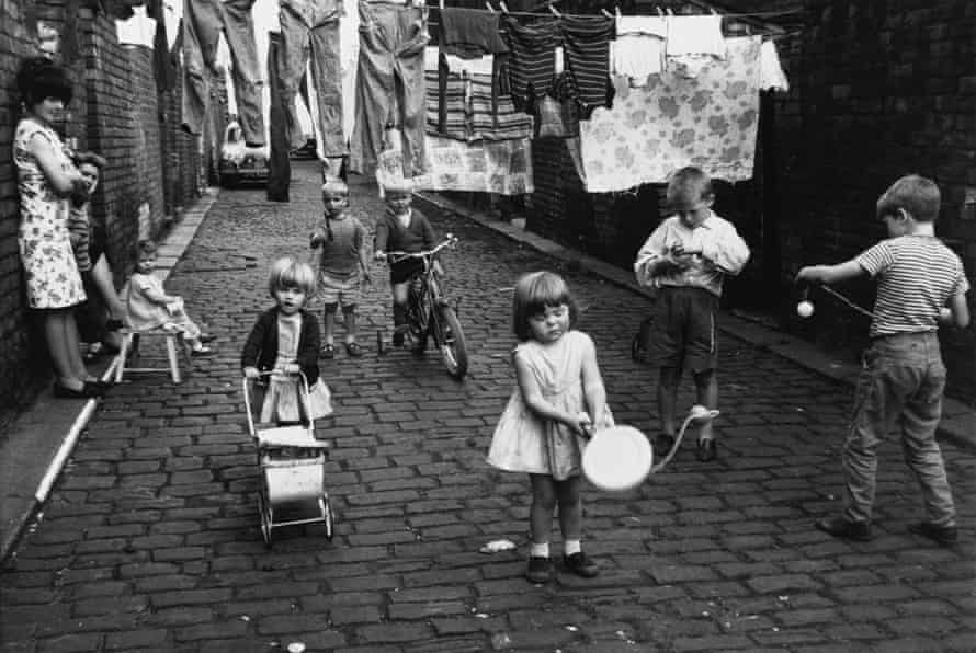 The cobbled lane between terraced houses in Chorlton-on-Medlock becomes both playground and laundry, 1966.