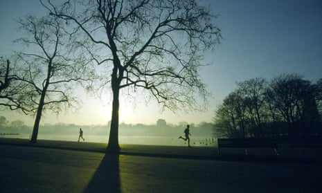 Runners at sunrise in a park by the river Thames in London.