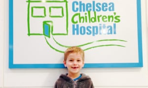 Child smiling in front of hospital sign