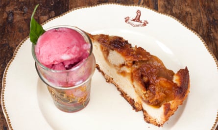 The pomegranate sorbet in a tall glass next to a slice of caramelised apple cake
