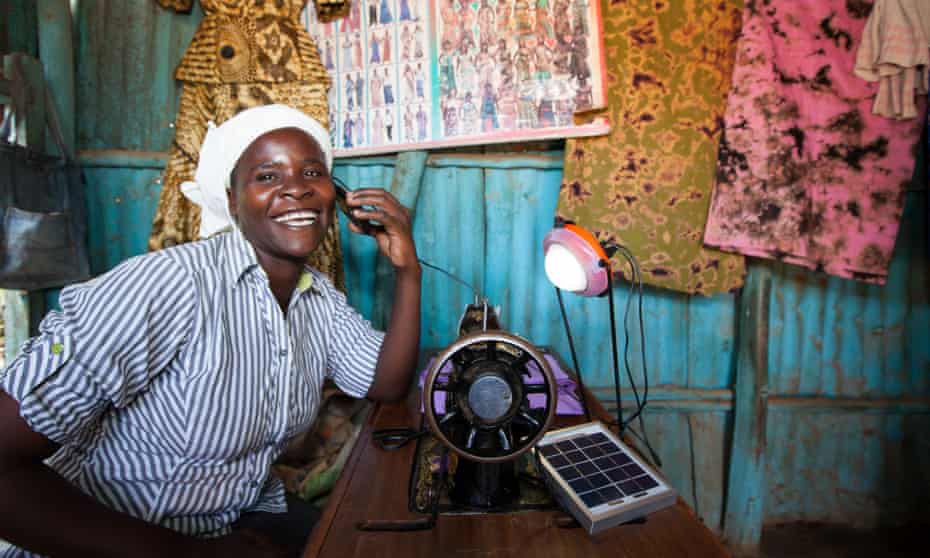 Rose Owino a tailor in Migori, Kenya uses a solar light to charge her phone