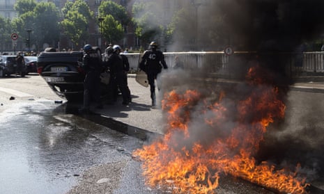 Riot police officers stand by an overthrown car during a taxi drivers demonstration in Paris.