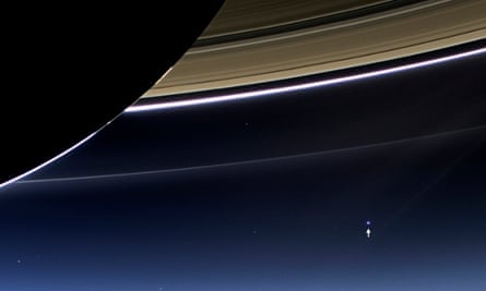 An image from the Cassini spacecraft shows the planet Earth, annotated by NASA with a white arrow, lower right, below Saturn's rings.