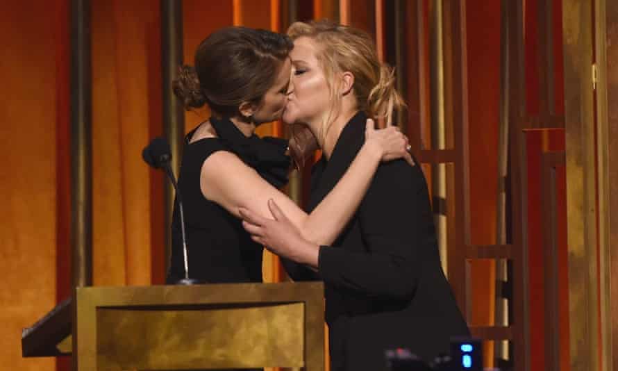 Comedians Tina Fey and Amy Schumer kiss on stage at the 74th Peabody awards ceremony.