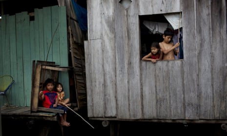 In this April 19, 2015 photo, children fish from their home sitting just above the water line in the Belen neighborhood of Iquitos, a community in Peru's Amazon nicknamed "Venice of the Jungle."