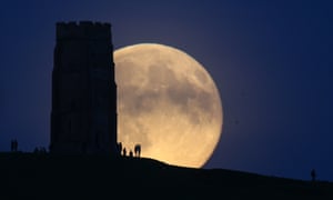 The moon rises over people gathered on Glastonbury Tor in Somerset, England.