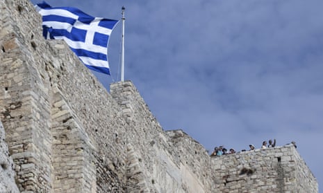 The Greek flag flies on the Acropolis hill in Athens.