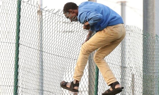 A man climbing over a fence on to the tracks near the Eurotunnel site at Coquelles in Calais, France.