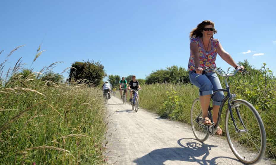 Woman cycles on a chalk path through the countryside