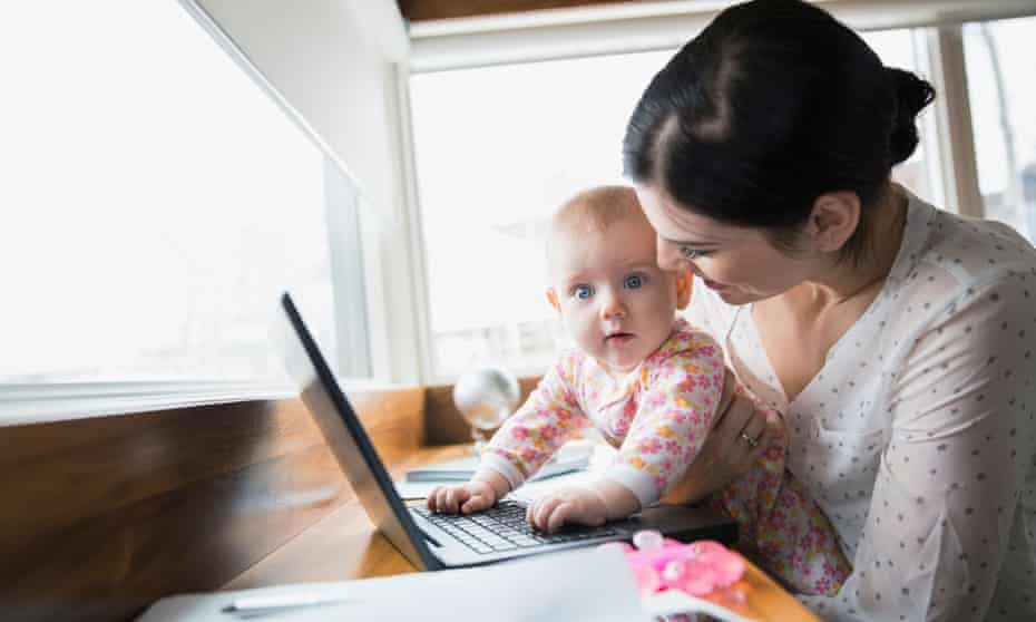 woman holding baby in front of laptop
