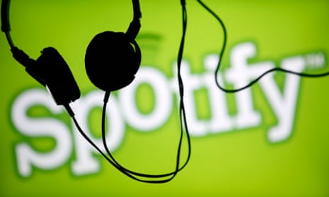 Headsets hang in front of a screen displaying a Spotify logo on it.