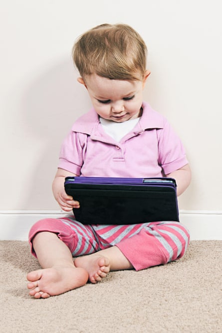 A baby girl plays on an iPad