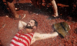 A man soaks up the atmosphere and tomato pulp as crowds throw tons of ripe tomatoes at each other.