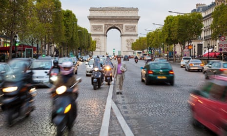 A man walks amid traffic on the Avenue des Champs-Elysees in Paris.