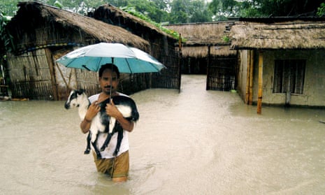 An Indian villager carries his goat to safety as he leaves his home to escape rising floodwaters.