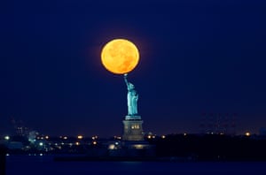 The moon sets behind the Statue of Liberty in New York