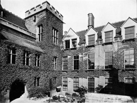 Black and white photograph of Cavendish Laboratory buildings; showing the corner of a courtyard, where two wings meet; there is a three-storey tower at the corner. much of the building is covered in a climbing plant.