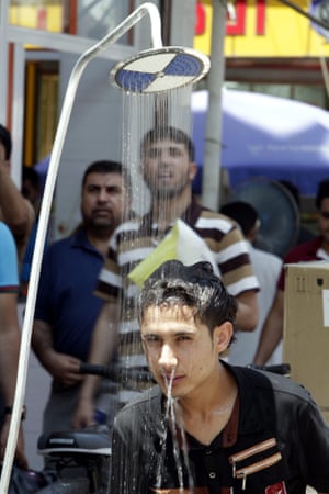 An Iraqi man cools off under a public shower at a street in central Basra city.