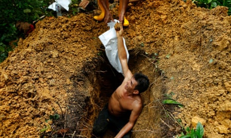 A grave digger hands over coffin nails while exhuming a grave at Bukit Brown Cemetery, Singapore.