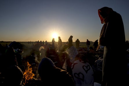 Refugees stand around a fire in a makeshift camp at a collection point in the village of Röszke, Hungary. Photograph: Marko Djurica/Reuters