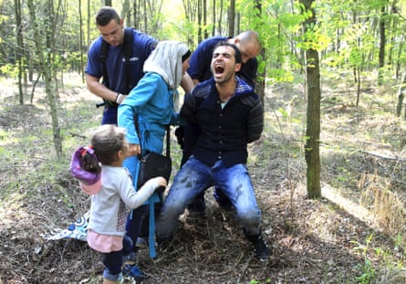 Hungarian policemen detain a Syrian refugee family after they entered Hungary at the border with Serbia, near Röszke. Photograph: Bernadett Szabo/Reuters.