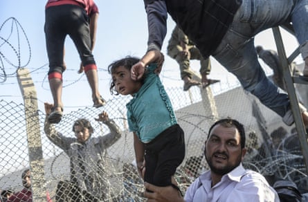 A Syrian child fleeing the war is lifted over border fences to enter Turkish territory illegally, near the Turkish border crossing at Akçakale in Sanliurfa province. Photograph: Bulent Kilic/AFP/Getty Images