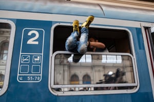 A boy is pulled through the window of a domestic Hungarian train. The refugees were later forced to get off the train by Hungarian police after all international trains were cancelled.