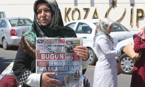 A woman holds a newspaper with the headline 'Operation against the media is the end of democracy' as they protest while police search the premises of the Koza Ipek media group,