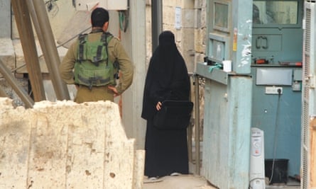 Hadeel al-Hashlamon stands next to a checkpoint in Hebron while a soldier allegedly asks to search her.