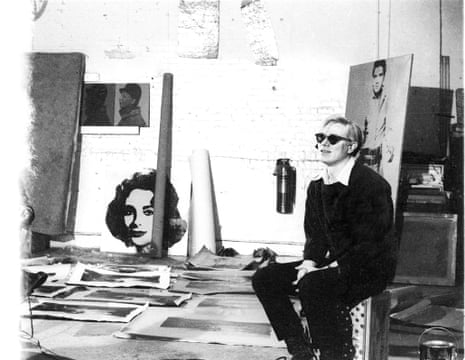 Andy Warhol with silver Liz Taylor, silver Elvis, and Electric Chair paintings at the original Factory studio, 1964.