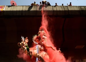 Indian devotees shower rose petals and coloured powder on a huge idol of elephant-headed Hindu God Lord Ganesha during its procession for an immersion in Mumbai on September 27, 2015. During the eleven-day Ganesh Festival Hindu devotees bring home idols of Lord Ganesha and offer prayers in temporary temples in order to invoke his blessings for wisdom and prosperity, culminating with the immersion of the idols in bodies of water, including the ocean on the last day. AFP PHOTO/ PUNIT PARANJPEPUNIT PARANJPE/AFP/Getty Images  wip
