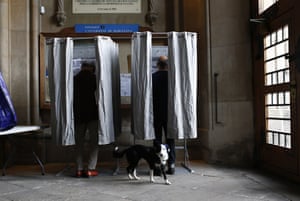A dog waits outside a voting booth at a polling station in Barcelona, Spain