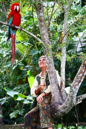 Rosa Maria Ruiz sits in a tree in the Amazon reserve she has protected against poaching, logging and mining, talking to a rescue macaw.