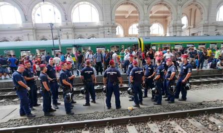 Hungarian police stand in front of people on a platform at the Keleti train station in Budapest.
