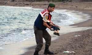 A paramilitary police officer carries the lifeless body of Aylan Kurdi, three, after a number of migrants died and a smaller number were reported missing after boats carrying them to the Greek island of Kos capsized.