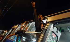 A man gestures as buses drive to the Hungarian border headed for Austria.