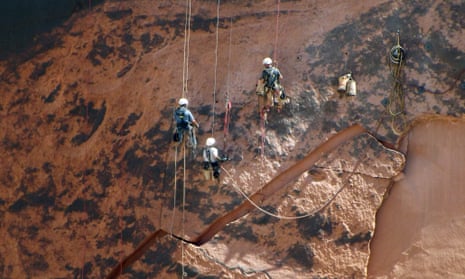 This photo taken Wednesday, Sept. 2, 2015, and provided by Frank Talbott shows workers stabilizing a sandstone wall along the Glen Canyon dam near Page, Ariz. The massive slab of rock is threatening to come crashing down at the base of the Arizona dam. The three-person crew has been working to stabilize the sandstone that forms the walls surrounding the Glen Canyon dam near the Arizona-Utah border.  The slab weighs 500,000 pounds and recently began to crack due to erosion. The area below the slab includes a boat ramp, and water and power facilities for the dam. (Frank Talbott via AP)
