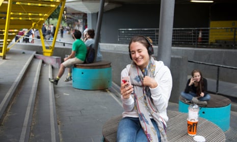 A young woman smiles while she enjoys a call with a friend on her smartphone.