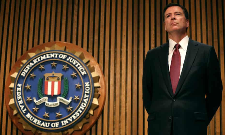 FBI director James Comey stands next to a Department of Justice plaque