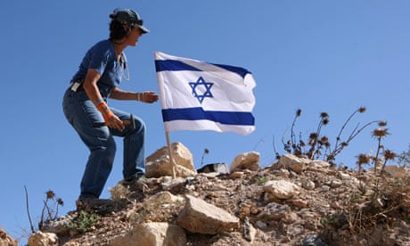 Israeli settler puts flag on a hilltop