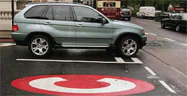 A 4x4 vehicle drives past a congestion charge sign