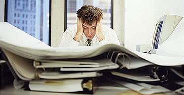 Stressed office worker with piles of paper work on his desk