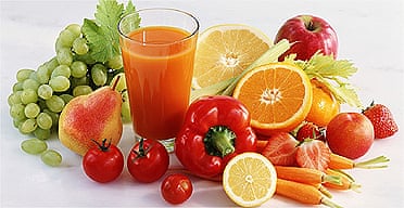 Glass of juice amongst various fruit and vegetables