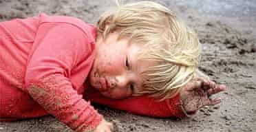 A child getting dirty on the beach