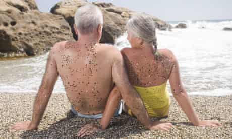 Elderly couple sitting on a beach on holiday