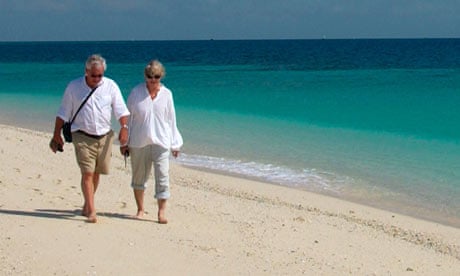 An elderly couple walk along a beach
