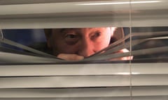 A man peering through a set of blinds