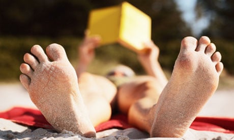 Woman lying on the beach reading a book